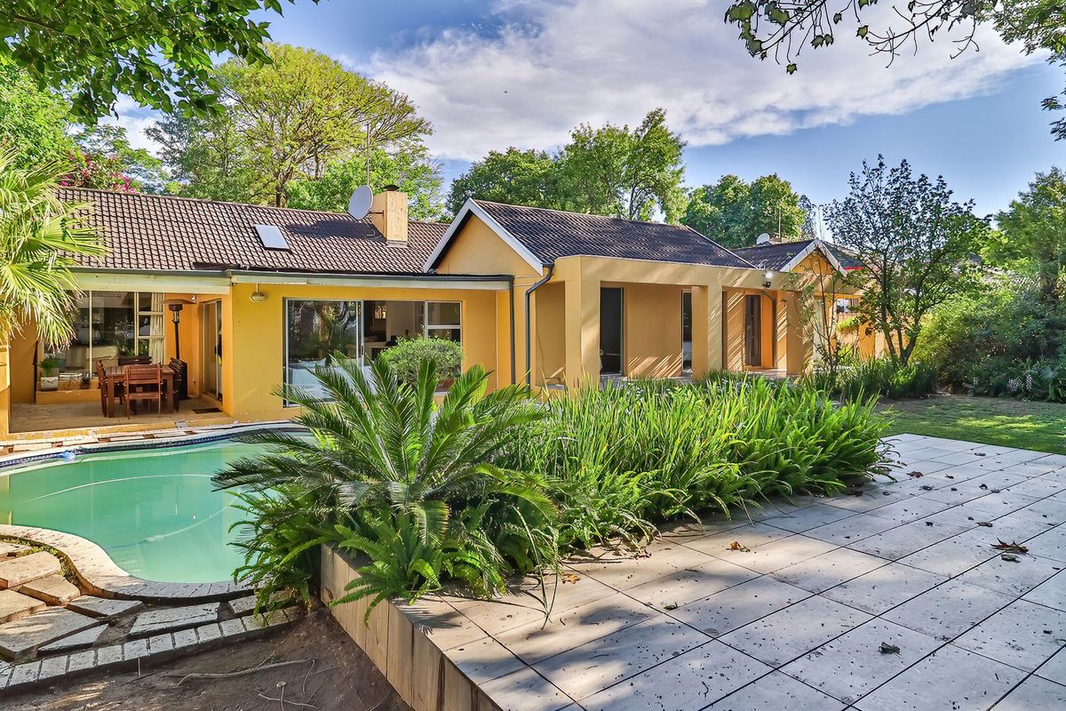 Rear view of the house featuring a swimming pool, tiled patio area, and established garden surroundings.