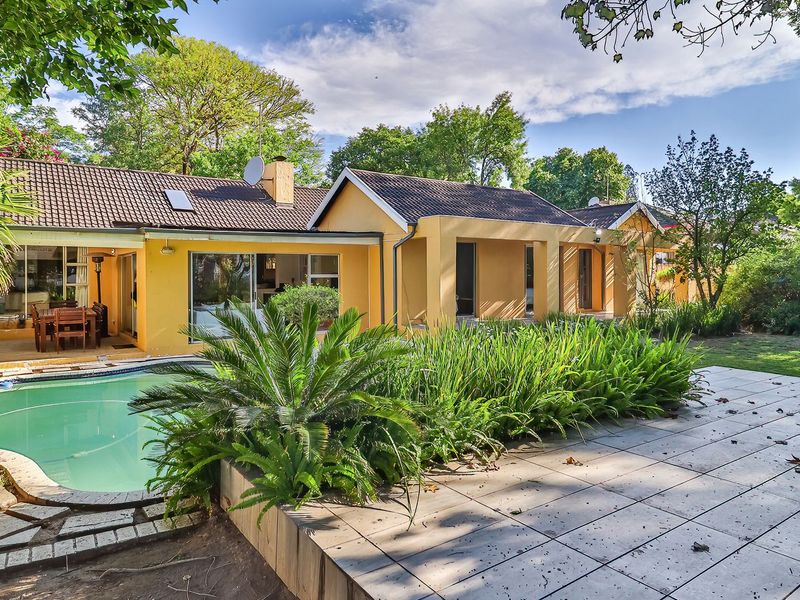 Rear view of the house featuring a swimming pool, tiled patio area, and established garden surroundings.