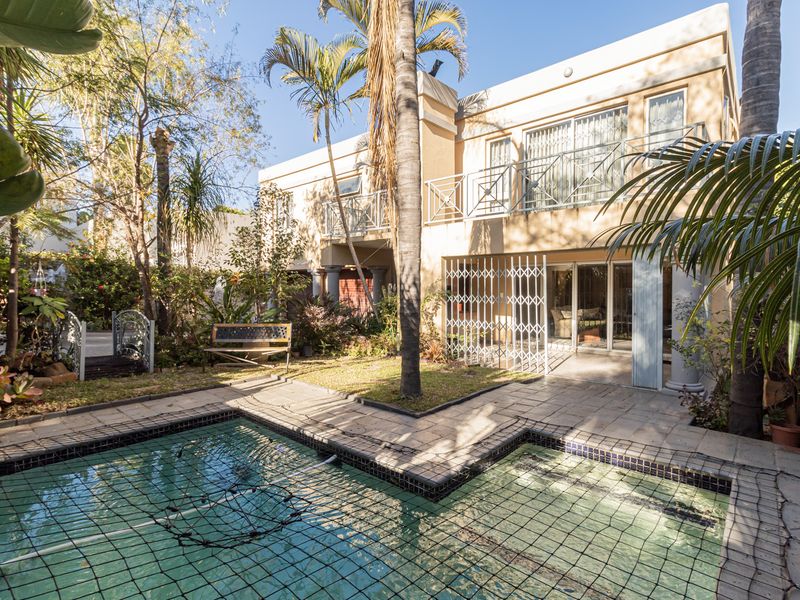 Rear view of the duet property featuring a swimming pool, paved patio area, and a balcony overlooking the private garden.