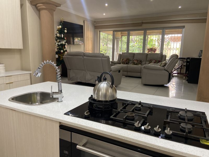 Spacious open-plan living area featuring a modern kitchen island with gas hob, integrated oven, and seamless flow to the lounge and patio.