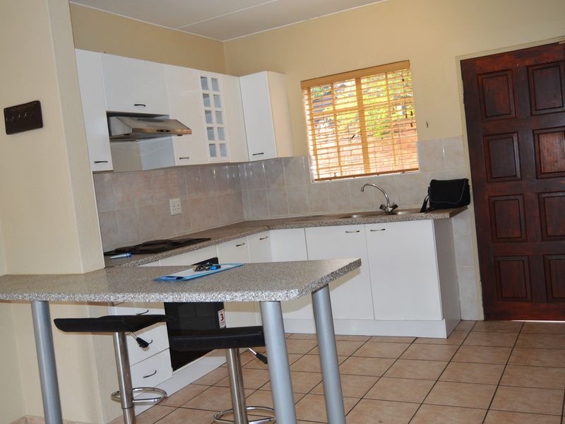 Functional kitchen featuring white cabinetry, laminate countertops, a breakfast bar, and tiled flooring, providing a practical layout for daily meal preparation.