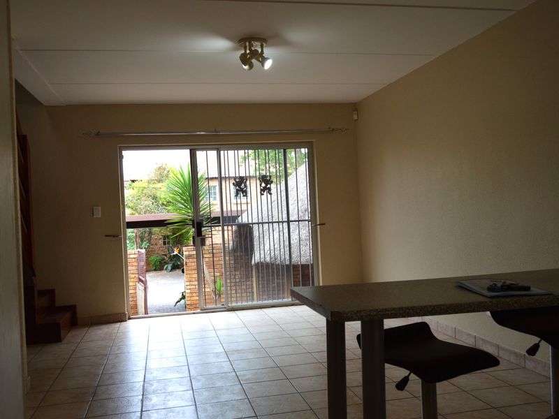 Spacious living area featuring tiled flooring and a large sliding glass door with security gate, providing direct access to the outdoor patio area.