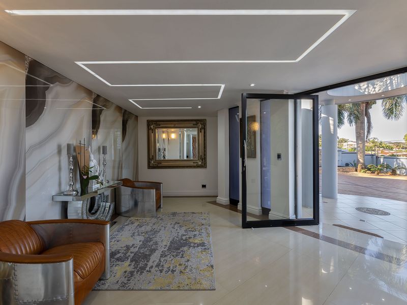 Modern entrance foyer featuring high-end marble-effect wall cladding, recessed linear ceiling lighting, and large format polished floor tiles with a seamless transition to the exterior.