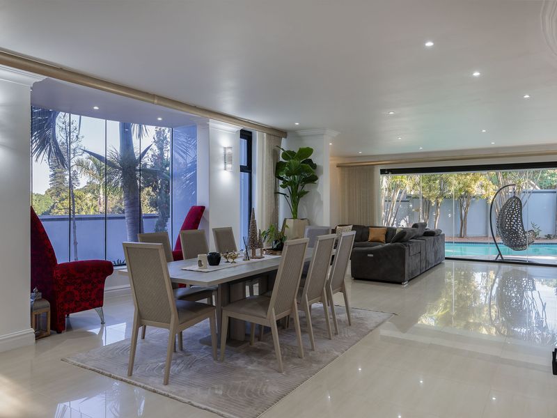 Spacious open-plan living and dining area featuring large-format polished floor tiles, recessed lighting, and expansive floor-to-ceiling glass doors opening to the pool area.