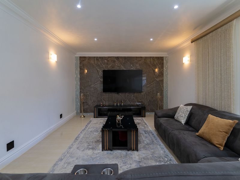 A modern living room featuring a striking marble feature wall, recessed downlighting, and elegant crown molding, creating a sophisticated and well-maintained space.