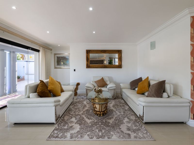 A bright and spacious living room featuring tiled flooring, recessed downlights, and large sliding glass doors that provide seamless access to the outdoor patio area.