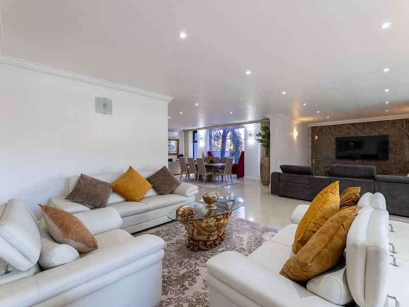 Spacious open-plan living and dining area featuring polished tiled floors, recessed downlighting, and a sophisticated marble feature wall.