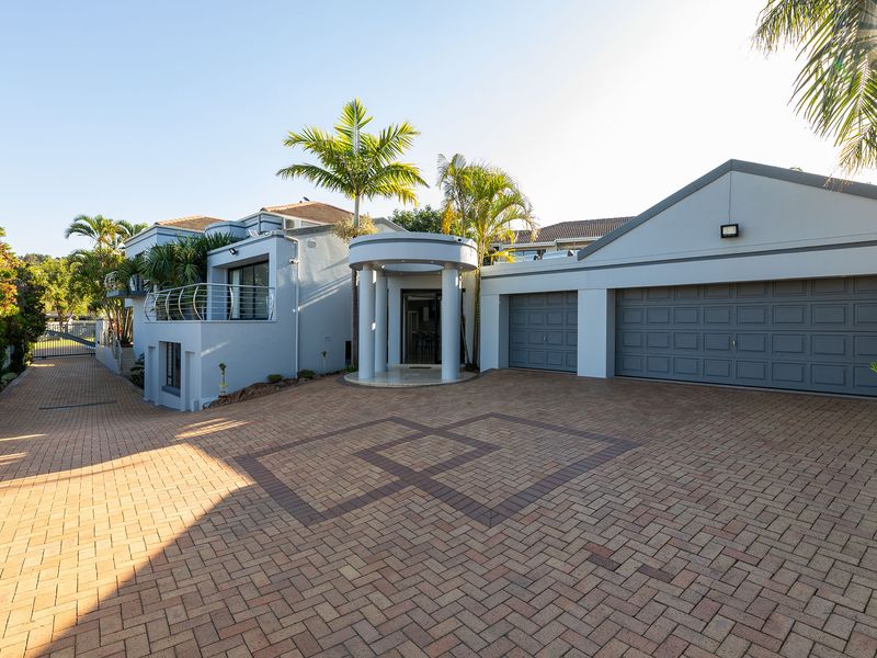 Front elevation of a modern house featuring a paved driveway, double garage, and a covered entrance with architectural columns.