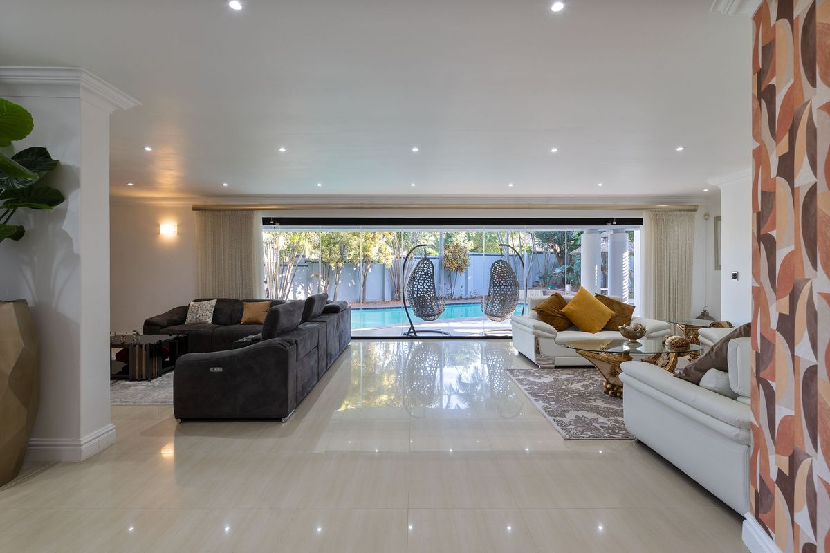 Spacious living area featuring large sliding glass doors that open to a pool view, complemented by polished porcelain tiles and modern recessed lighting.