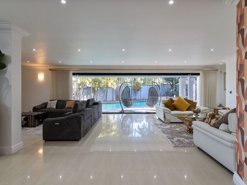 Spacious living area featuring large sliding glass doors that open to a pool view, complemented by polished porcelain tiles and modern recessed lighting.