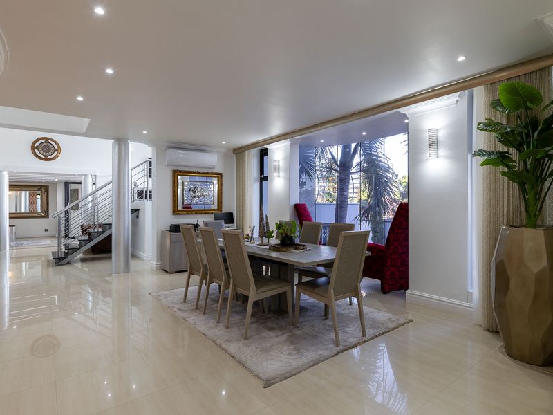 Spacious dining area featuring polished porcelain flooring, recessed lighting, and an open-plan layout with a modern staircase and integrated climate control.