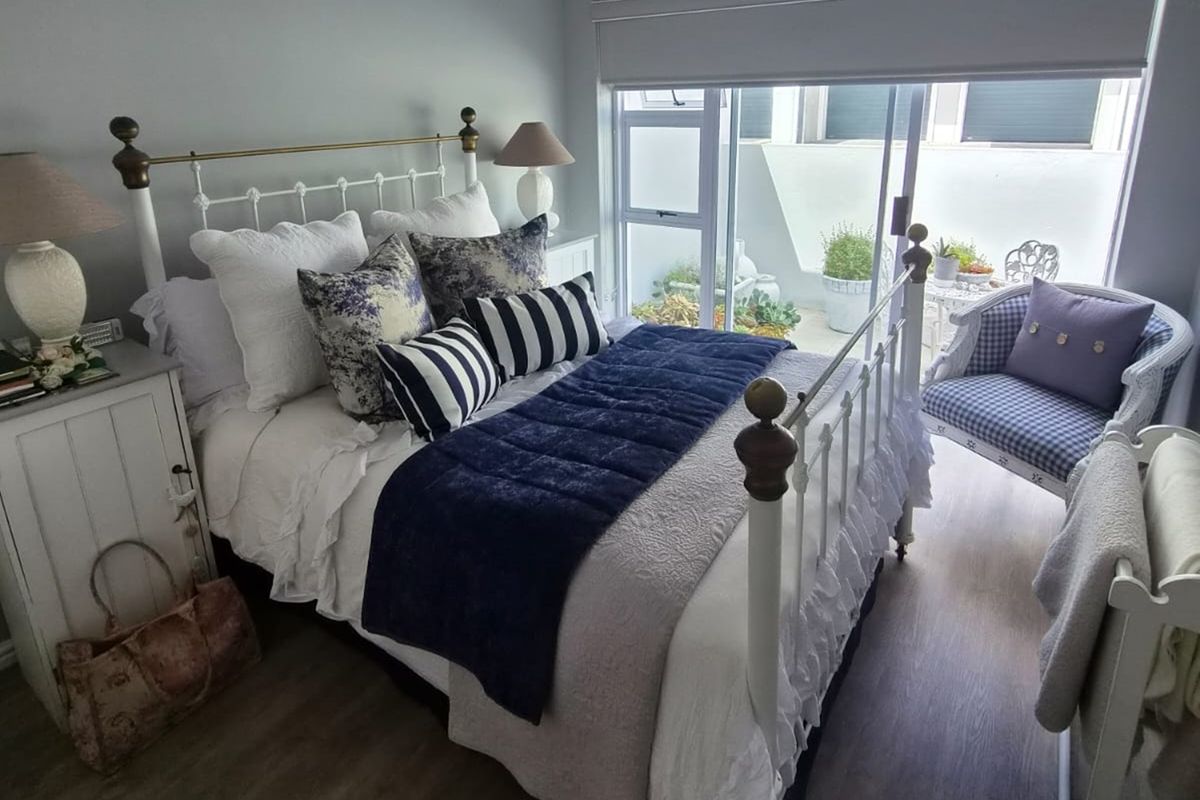 A well-maintained bedroom featuring laminate flooring, a tongue and groove ceiling, and a sliding glass door providing access to an outdoor patio area.