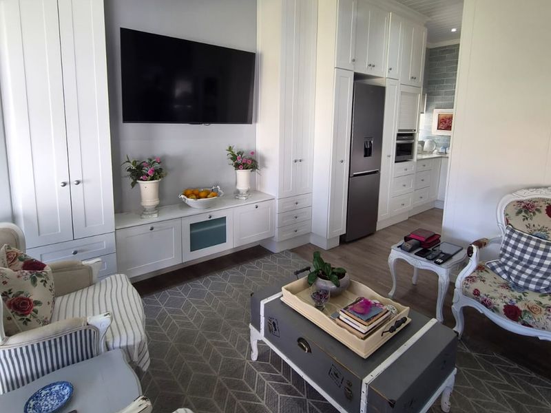 A bright open-plan living area featuring custom built-in cabinetry, recessed lighting, and a seamless transition into a modern kitchen with integrated appliances.