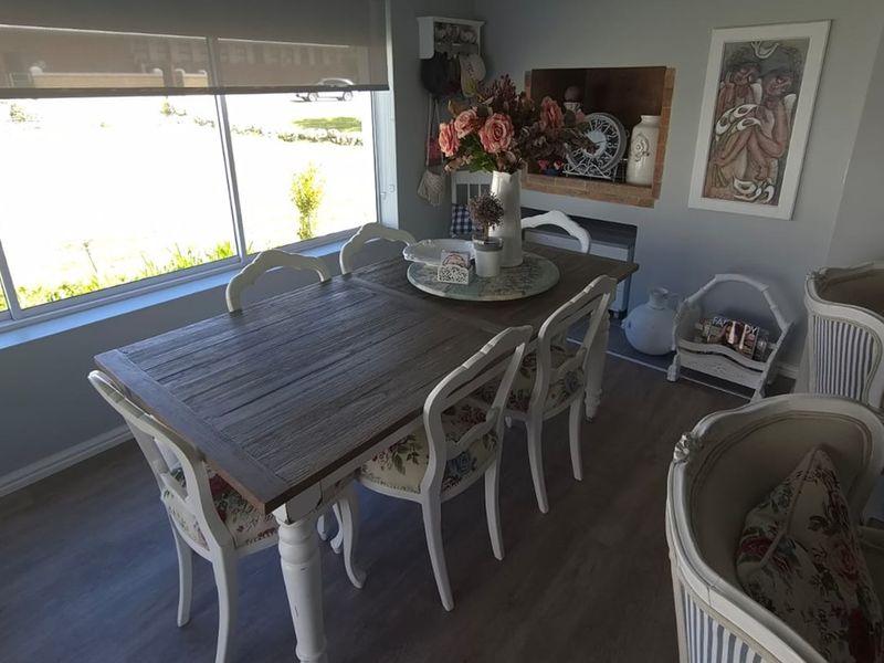 A bright dining area featuring laminate flooring, a large window with a roller blind, and a decorative recessed wall niche.
