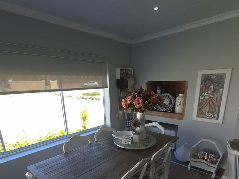 A well-maintained dining area featuring a built-in wall niche, crown molding, and a large sliding window with a roller blind.