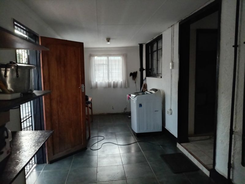 A functional laundry area featuring tiled flooring and essential plumbing connections, providing a practical space for utility tasks.