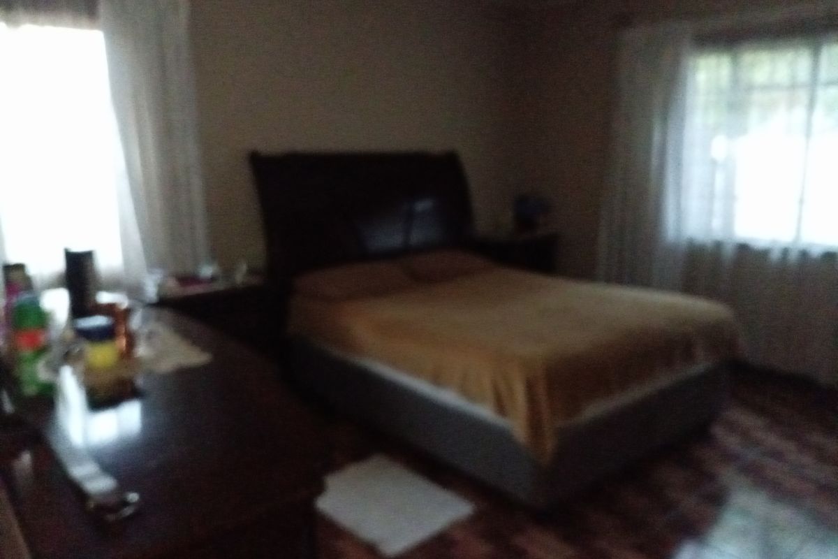 A bedroom featuring tiled flooring and natural light from two windows.