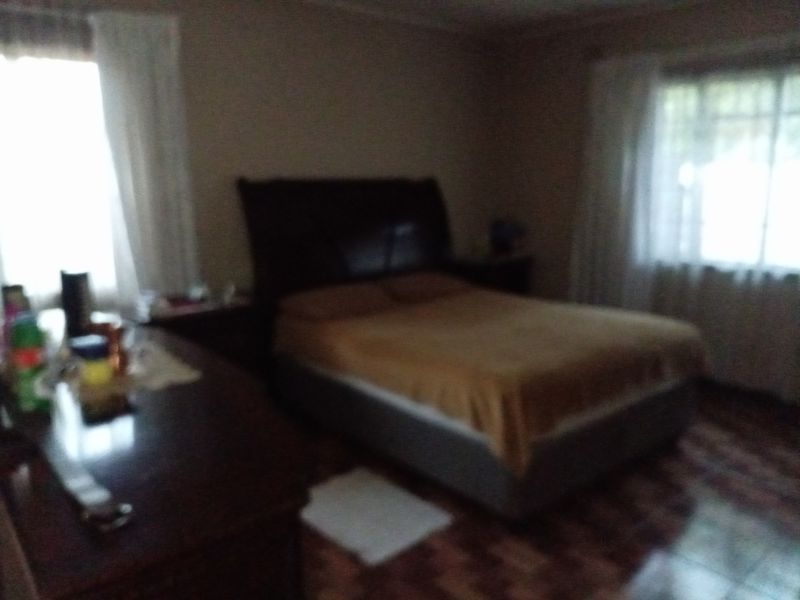 A bedroom featuring tiled flooring and natural light from two windows.