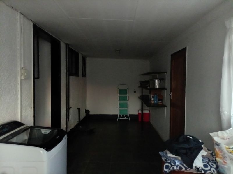 A functional laundry room featuring tiled flooring, built-in shelving, and dedicated plumbing connections for a washing machine.
