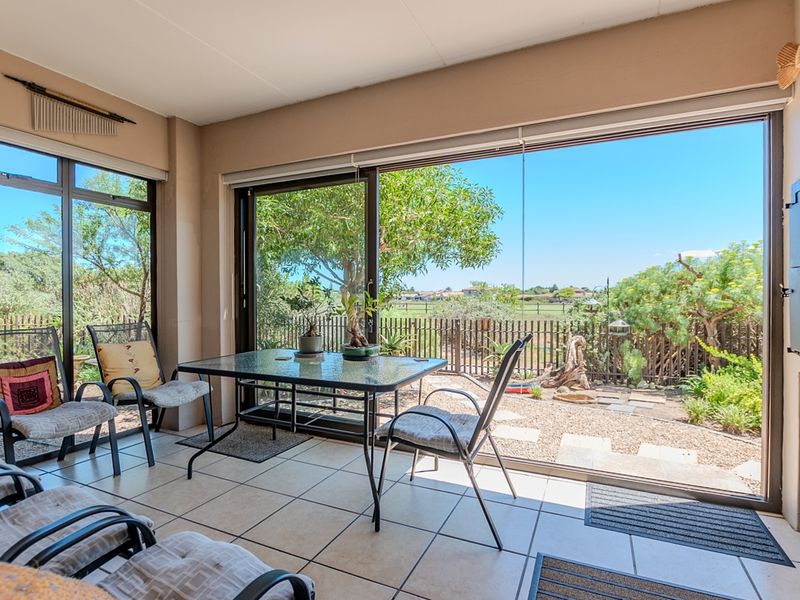 A bright, enclosed patio featuring large sliding glass doors that provide seamless access to the garden and scenic outdoor views.