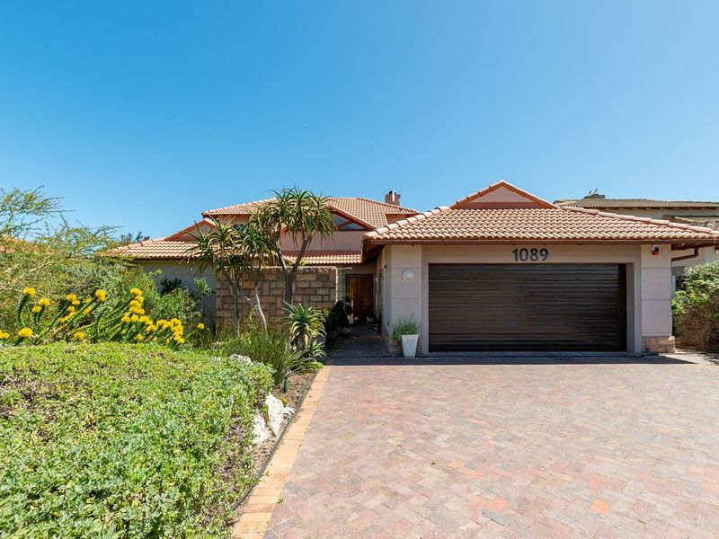 Front elevation of a well-maintained house featuring a brick paved driveway, automated garage, and established garden.