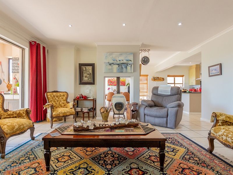 Spacious open-plan living area featuring tiled floors, a central fireplace, and seamless flow to the kitchen and outdoor patio area.