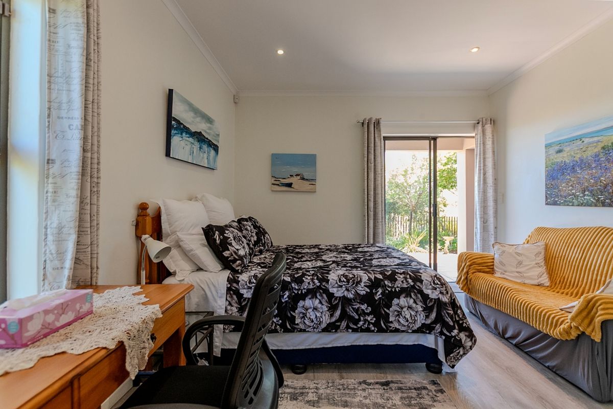 A well-lit bedroom featuring laminate flooring, recessed downlights, and a sliding glass door providing direct access to the outdoor patio area.
