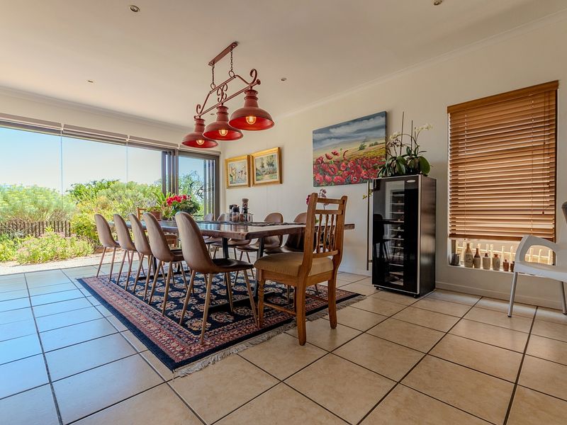 Spacious dining area featuring large stacking glass doors that open to the garden, tiled flooring, and modern recessed lighting.