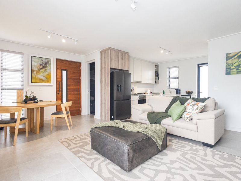 Modern open-plan living area featuring a sleek kitchen with built-in appliances, tiled flooring, and a bright, contemporary layout.