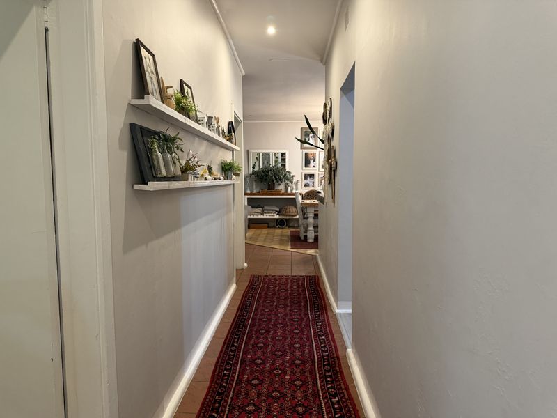 A functional hallway featuring neutral wall finishes, recessed downlighting, and built-in wall shelving, providing a clear transition between living spaces.
