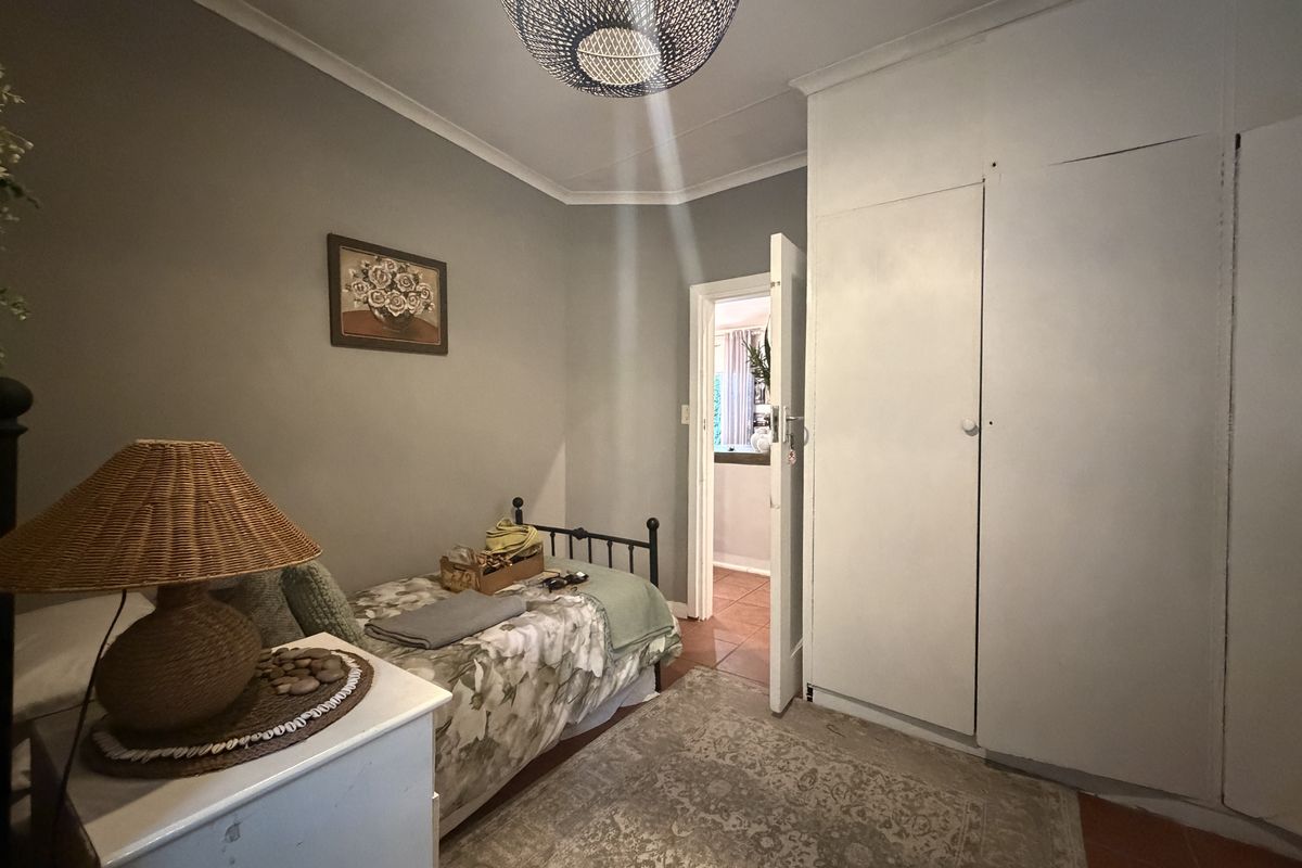 A functional bedroom featuring built-in cupboards, tiled flooring, and cove cornicing, offering a neutral base for personalization.