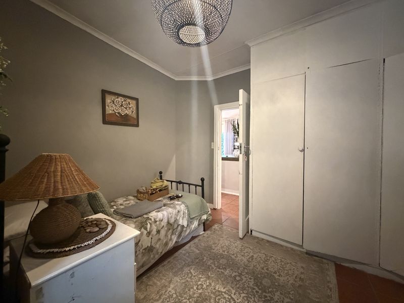 A functional bedroom featuring built-in cupboards, tiled flooring, and cove cornicing, offering a neutral base for personalization.