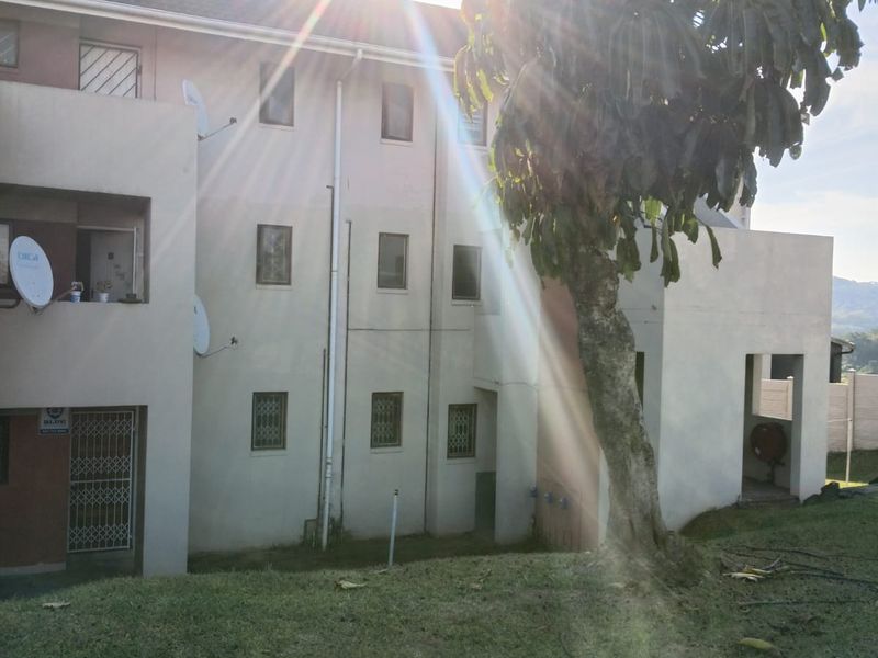 Rear view of the apartment building featuring a lawn area, security gates, and exterior building infrastructure.