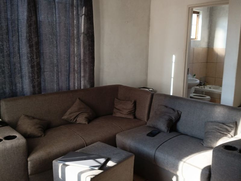 A living room area featuring ceramic floor tiles and direct access to an adjacent bathroom.