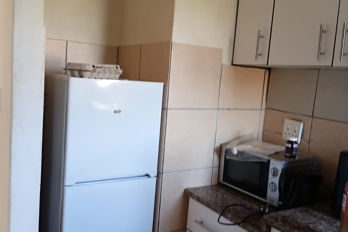 A compact kitchen area featuring built-in cabinetry, granite countertops, and tiled backsplash, offering functional storage and preparation space.