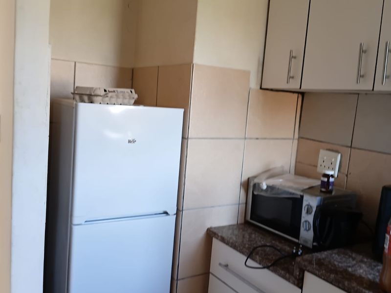 A compact kitchen area featuring built-in cabinetry, granite countertops, and tiled backsplash, offering functional storage and preparation space.