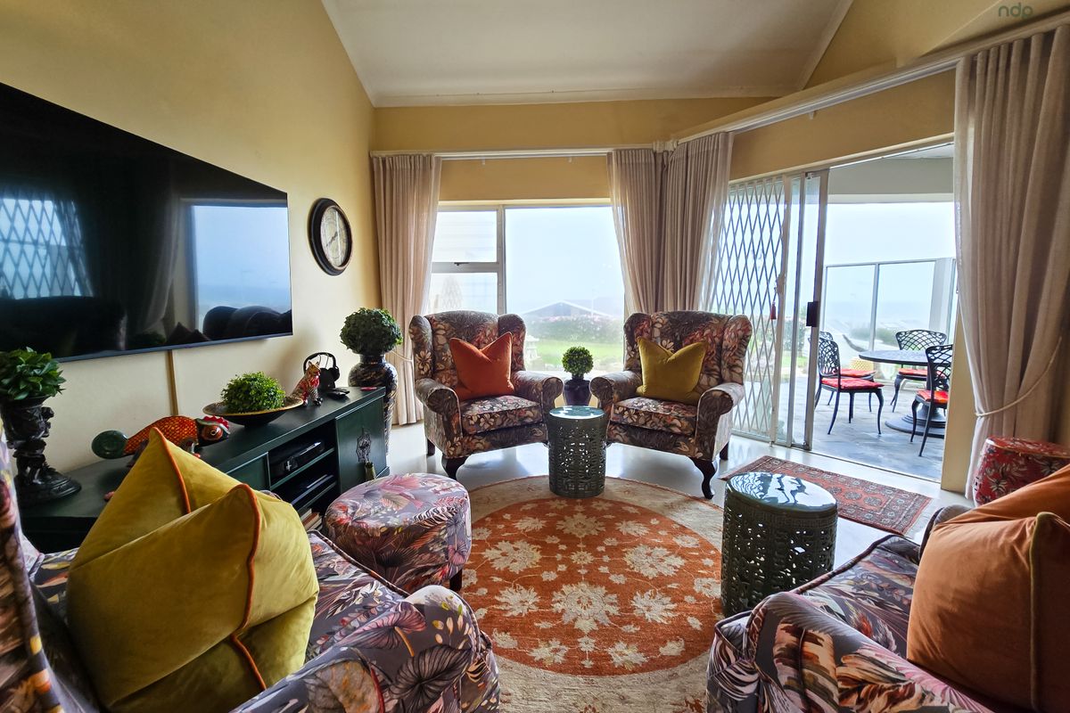 A cozy living room featuring a vaulted ceiling, large windows, and sliding glass doors that open onto a patio with outdoor views.