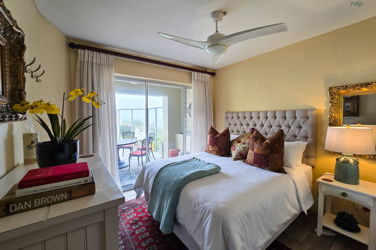 A well-lit bedroom featuring a ceiling fan and sliding glass doors that open onto a private balcony, providing natural light and outdoor access.