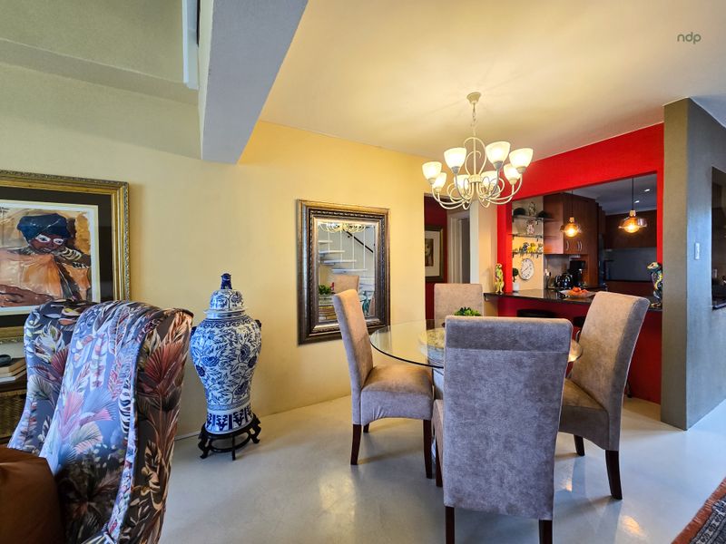 Open plan dining area featuring a breakfast bar, integrated kitchen cabinetry, and a staircase, with a bright red accent wall.