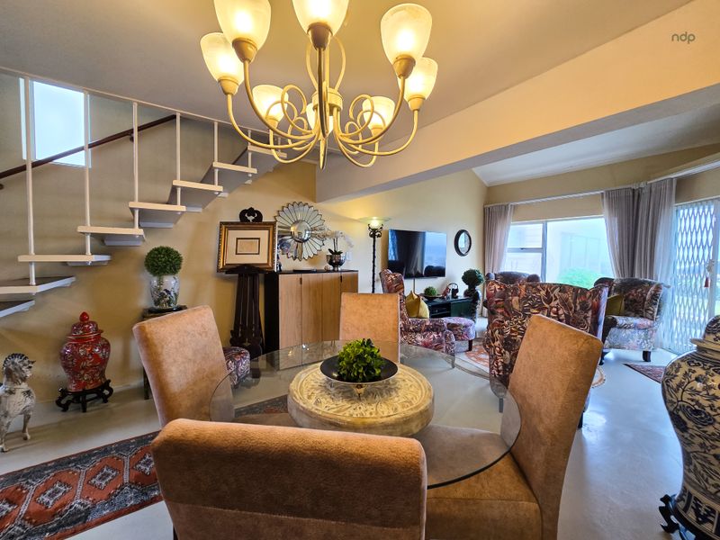 Open plan living and dining area featuring a staircase, chandelier lighting, and sliding glass doors leading to the exterior.