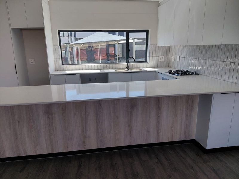 Modern kitchen featuring sleek white and wood-grain cabinetry, quartz countertops, a built-in gas hob, and a stylish subway tile backsplash.