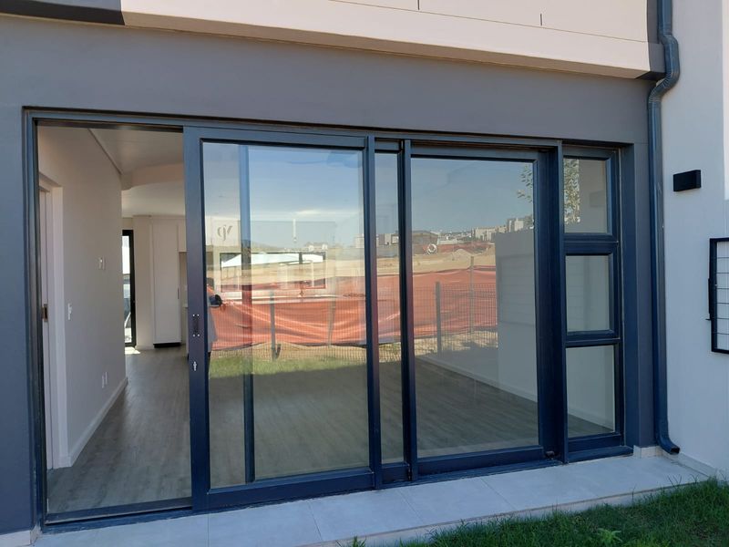 Rear view of the townhouse featuring large sliding glass doors opening onto a tiled patio area with modern exterior finishes.