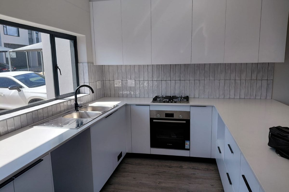 Modern kitchen featuring white cabinetry, quartz countertops, subway tile backsplash, and integrated stainless steel appliances, offering a clean and functional workspace.