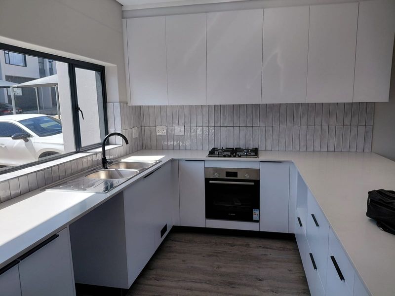 Modern kitchen featuring white cabinetry, quartz countertops, subway tile backsplash, and integrated stainless steel appliances, offering a clean and functional workspace.