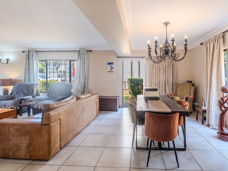 Spacious open-plan living and dining area featuring tiled flooring, a decorative chandelier, and direct access to the outdoor space through a sliding door.