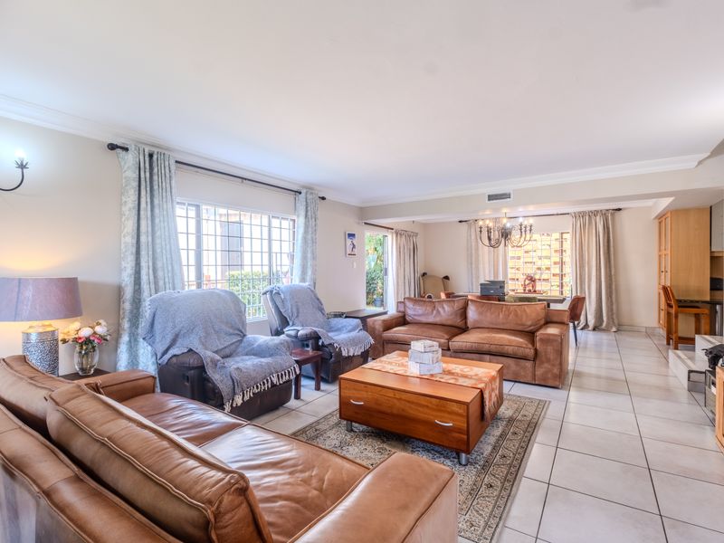 Spacious open-plan living and dining area featuring neutral tiled flooring, large windows for natural light, and integrated air conditioning.