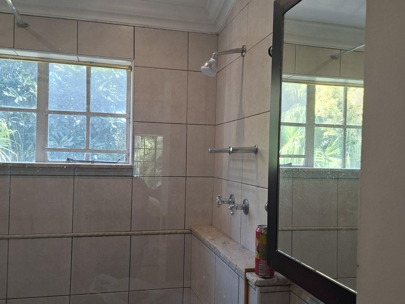 A bathroom featuring tiled walls, a shower, and a built-in vanity. The space appears to be undergoing maintenance or renovation.