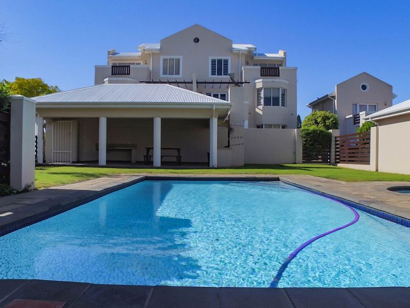 A well-maintained rear garden featuring a swimming pool and a spacious covered patio area, ideal for outdoor entertaining.