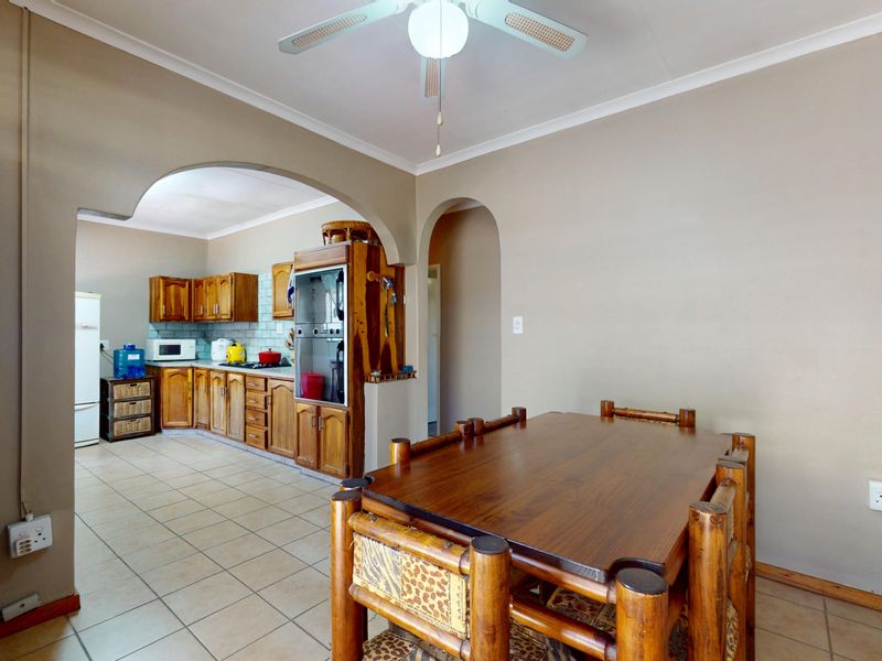 Open plan kitchen and dining area featuring traditional wooden cabinetry, tiled flooring, and a central archway connecting the functional kitchen space to the dining area.
