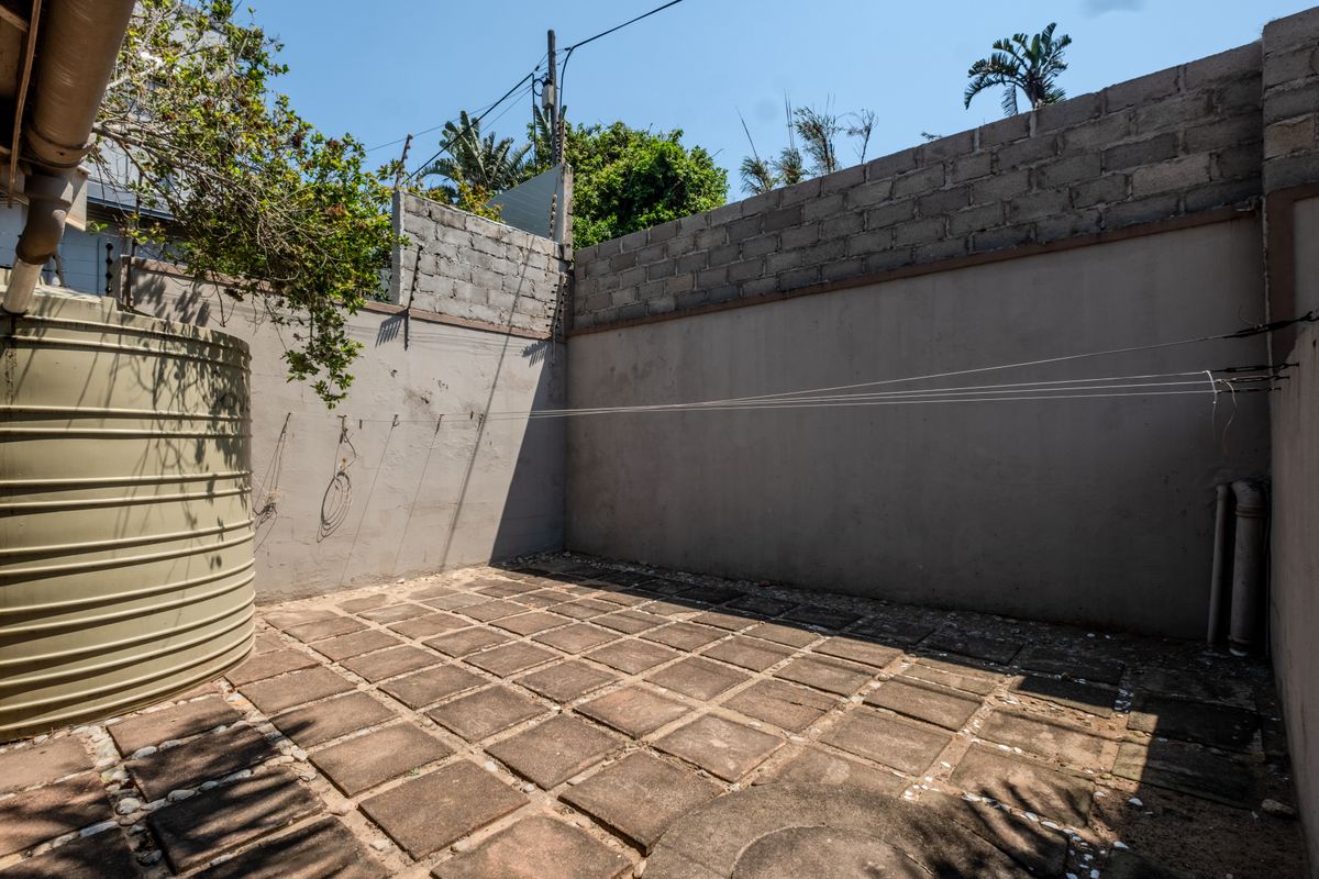 A private rear courtyard featuring paved flooring, a water storage tank, and perimeter walling with electric fencing.